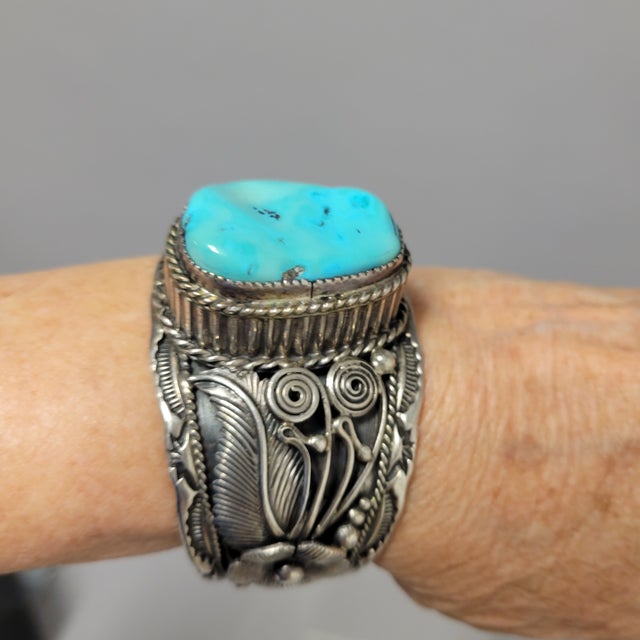 This stunning vintage Navajo cuff bracelet features a heavy-gauge sterling silver band adorned with a natural, freeform...