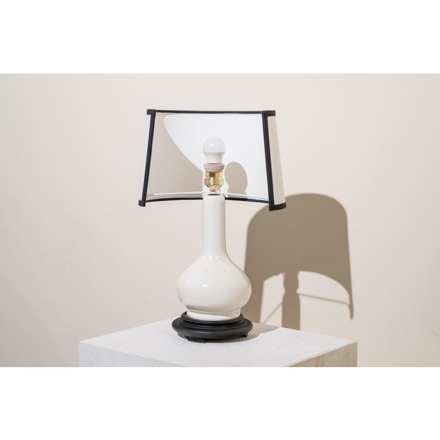 A 1960s vase table lamp. The structure consists of, from bottom to top, a circular, molded black wooden base and a...