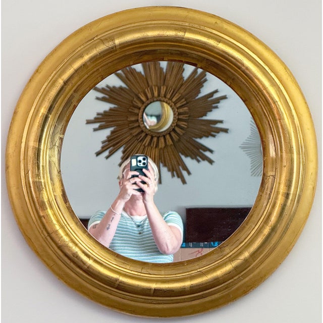 A fine English round or circular wall mirror from the Regency era, circa 1820, featuring a deep giltwood frame with an...