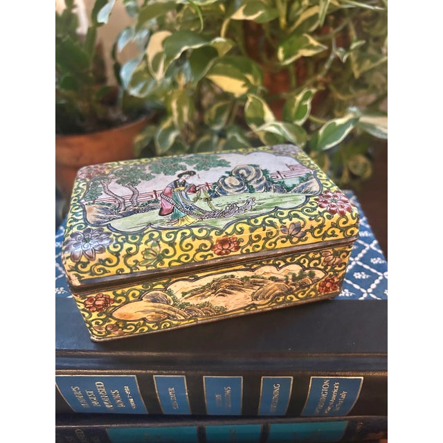 This is a Chinese Canton enamel-on-copper box featuring a yellow background with scrolling green foliage and pink floral...