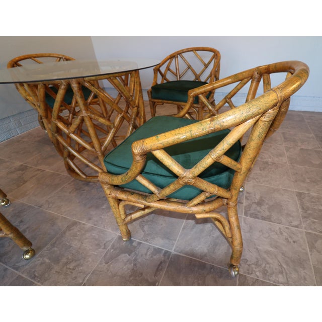 A refined mid-century rattan dining set attributed to Ficks Reed, featuring four barrel-back dining armchairs and a round...