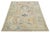 This hand-knotted wool rug features a beige background with a blue frame adorned with multicolored accents in an all-over...