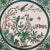 A beautifully painted porcelain plate featuring a central scene of birds perched among flowering branches, with...