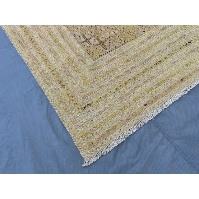 This minimalist Gabbeh rug features small scattered cross and star motifs in soft amber and rust, floating across a softly...