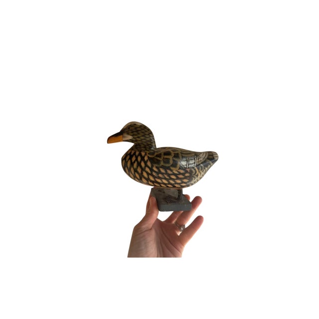 Vintage hand-carved and hand-painted wooden duck decoy mounted on a display base. The body appears to be carved from a...