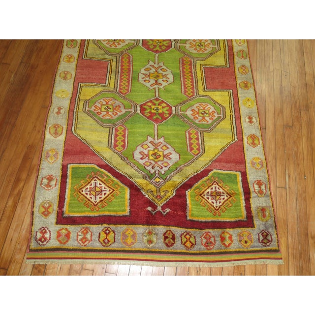 A mid 20th cenutry Turkish Konya rug featuring a bright apple green color. The medallion is a mustard, the ground is red...