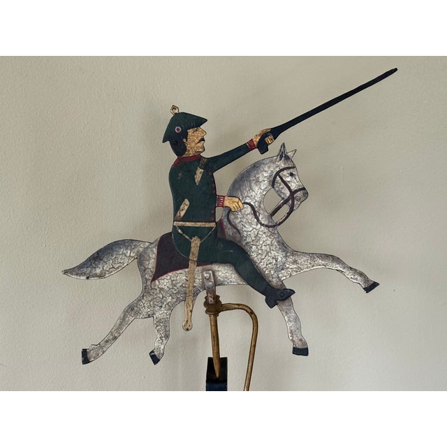 A charming vintage folk art sculpture of a soldier charging on a galloping horse, captured in a kinetic balancing...