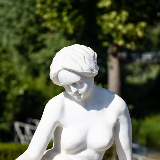 Marble sculpture of a reclining female nude. The figure portrays a contemplative woman in a relaxed, classical pose, with...