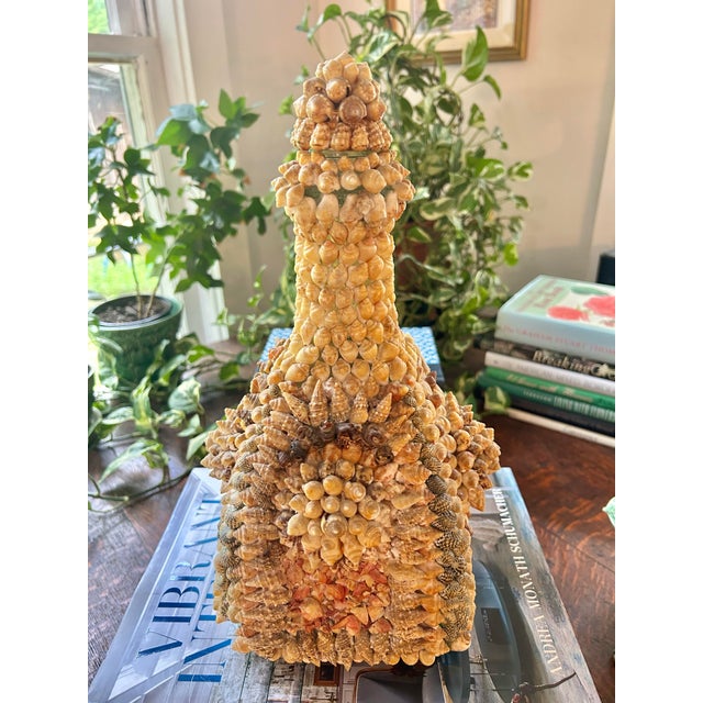 Shell encrusted items are fascinating. This particular one appears to be a decanter with shells applied in a symmetrical...