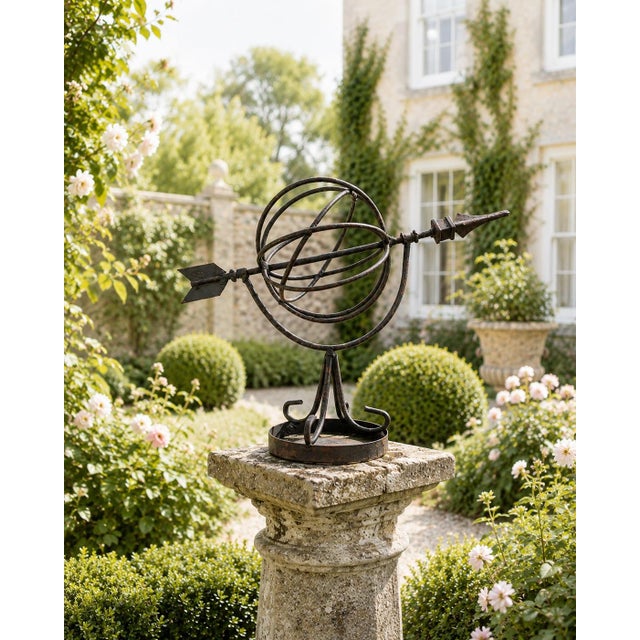 A sculptural vintage wrought iron armillary sundial with wonderfully aged surface patina and a graceful arrangement of...