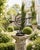 A sculptural vintage wrought iron armillary sundial with wonderfully aged surface patina and a graceful arrangement of...