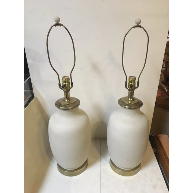 A pair of Metal and brass pair of lamps. Features rounded metal body in cream with eggshell finish and brass base and...