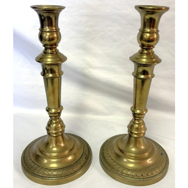 Elegant pair of antique French candlesticks from the early 20th century. They are made of heavy brass with an embossed...