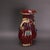 Ornate sculptural ceramic vase with rich oxblood red fluted glaze and subtle purple speckling. It features polished gilt...