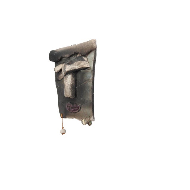 A handmade pottery wall sculpture featuring an expressive abstract face with sculptural relief details and earthy matte...