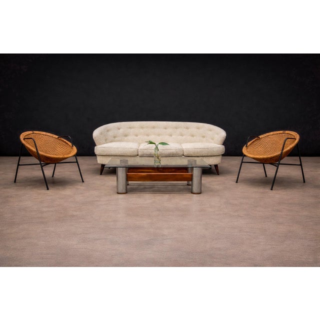 Executed with slender iron frames and handwoven wicker seats, this pair of armchairs reflects the Brazilian modernist...