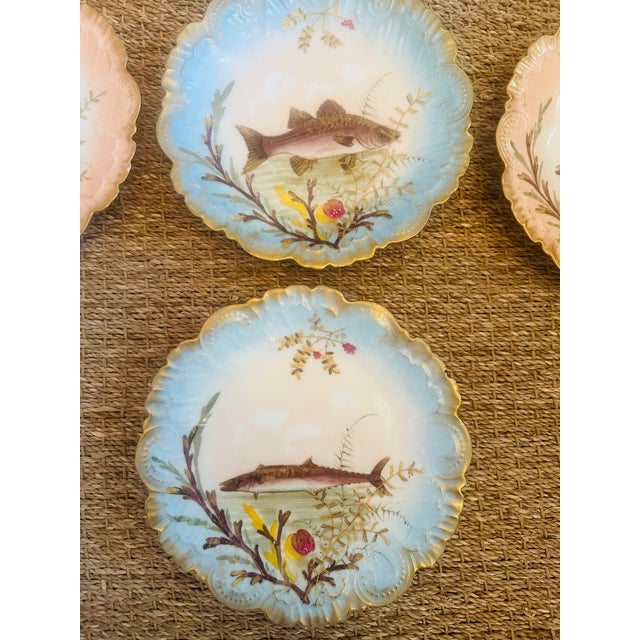 A charming antique set of Limoges France porcelain plates featuring delicately scalloped edges with soft pastel washes of...