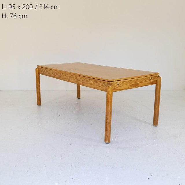 Rectangular larch wood table with turned legs and rounded corners, equipped with two retractable side extensions that...