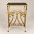 An elegant Hollywood Regency gilt metal side table with beveled mirrored glass top and an integrated magazine rack....