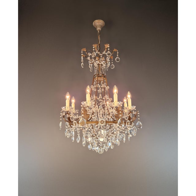 An antique crystal chandelier with an open, elegantly curved structure and rich crystal ornamentation. Stylistically, we...