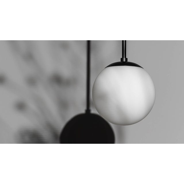 A single globe hangs from a linear brass fixture; a perfect dewdrop. Inspired by the design of classic brasserie lights,...