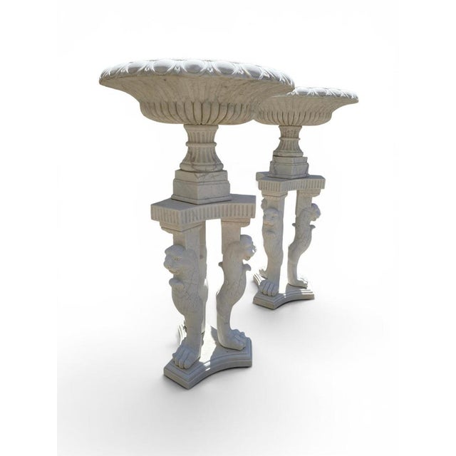 Exceptional pair of monumental Greco-Roman style kraters carved in soft marble and raised on impressive tripod pedestals...