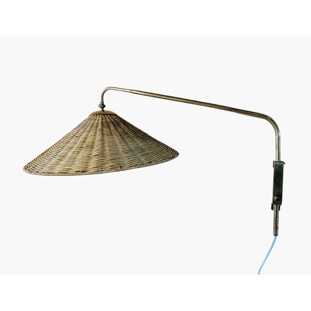 This vintage wall lamp, made by Valinte in the 1950s, beautifully combines brass and rattan into a warm and inviting...