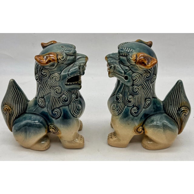 A striking matched pair of ceramic Foo Dogs (Shishi / Guardian Lions), glazed in celadon-blue and tan with expressive...