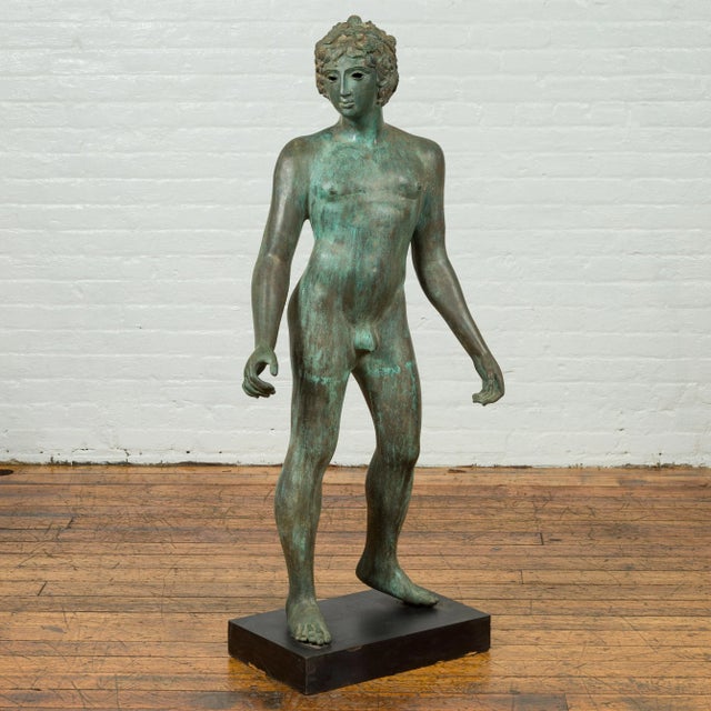A vintage Greco-Roman style bronze nude statue from the 20th century with verde patina and wooden pedestal base. Created...