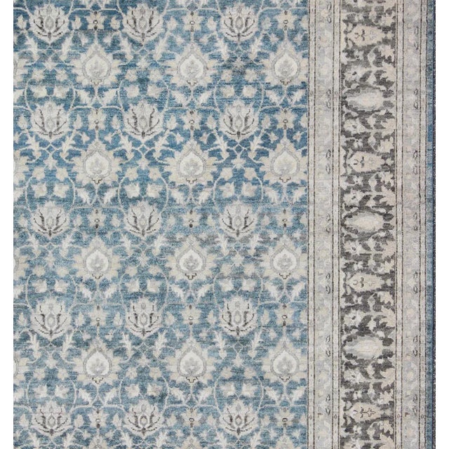 This hand knotted Tabriz rug features a beautiful all-over design rendered in grays, silver, and charcoal and blue tones....