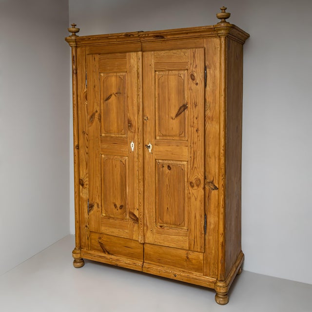Softwood wardrobe with two doors and gracefully rounded corners, topped with decorative finials. Each door features double...