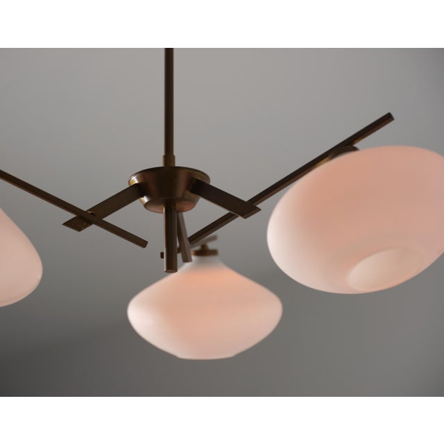 Elegant Italian chandelier from the 1950s, featuring a sculptural brass structure with a beautiful, even patina and three...