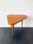 This asymmetrical wooden side table is designed in a mid-century modern style, with a three-sided top, softly rounded...