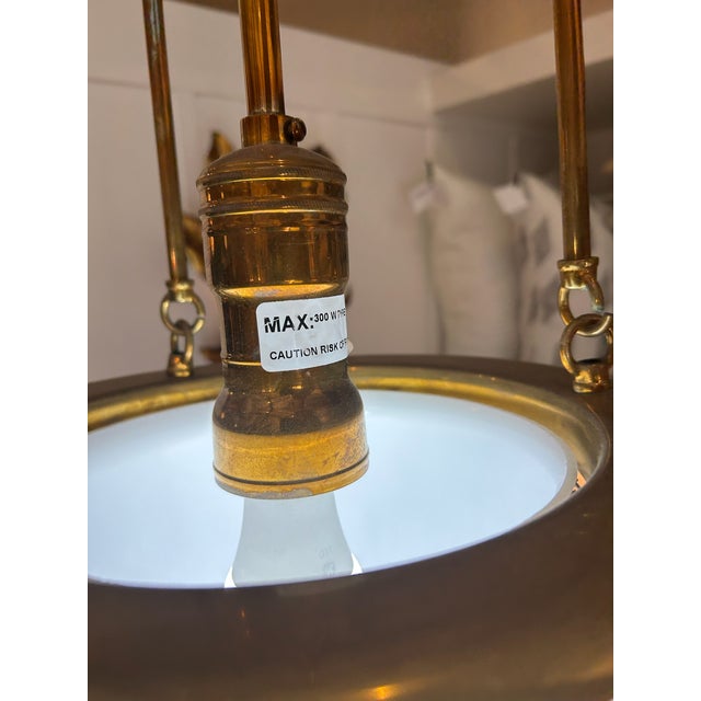 Unlacquered brass hood pendant with a 12-inch opal glass globe. The globe is wrapped in a hexagonal wire mesh pattern. The...