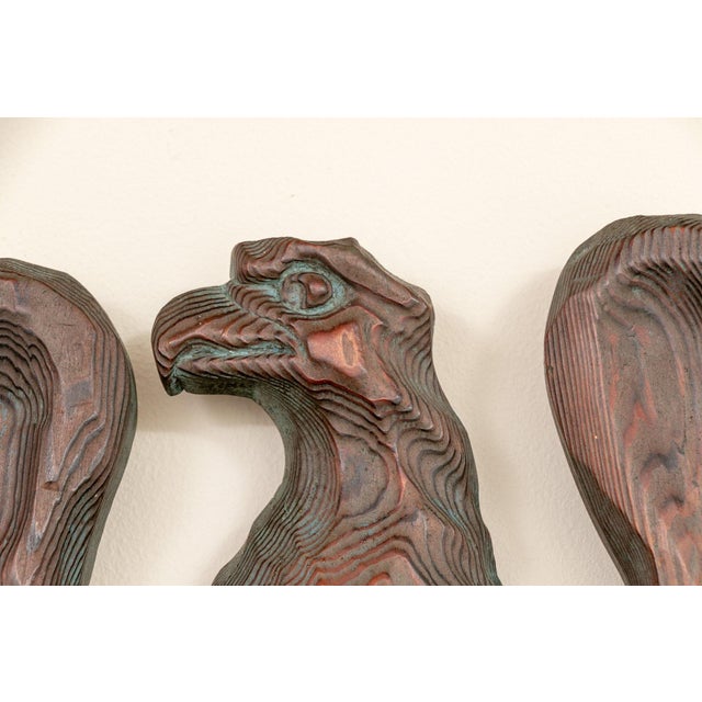 A stylized carved wood eagle wall plaque with dramatically emphasized wood grain, sculpted into a shield-like body with...