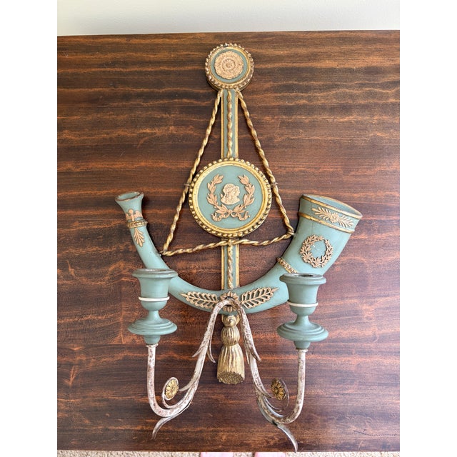 A beautifully detailed pair of Italian neoclassical wall sconces featuring a soft celadon green painted finish accented...