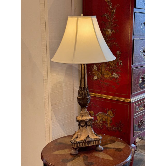 Carved wood altar stick form lamp with tapering shaft above a stepped triangular base raised on three bun feet. Decorated...