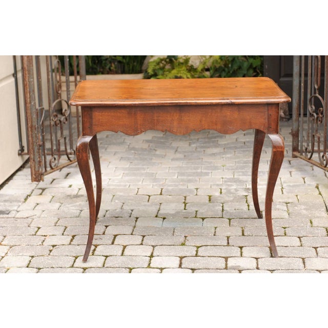 A French Louis XV style oak side table with single drawer, scalloped apron and cabriole legs from the early 19th century....