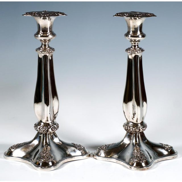 Two extraordinary festive Biedermeier silver candlesticks on a four-pass-shaped, flared, and domed base, with floral...