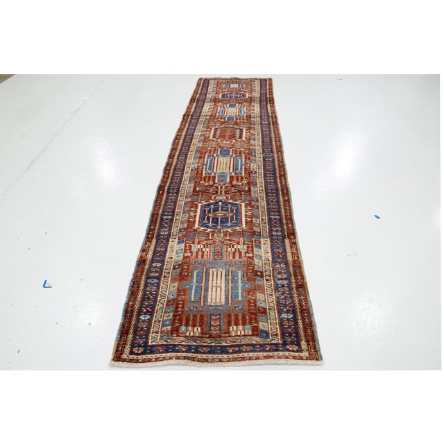 This Vintage Persian Heriz hand-knotted wool runner has a red-rust field with blue and beige accents throughout the...