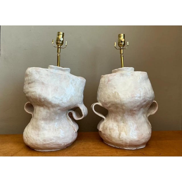 This pair of table lamps embraces an intentionally irregular, hand-built silhouette, each ceramic base rising and swelling...