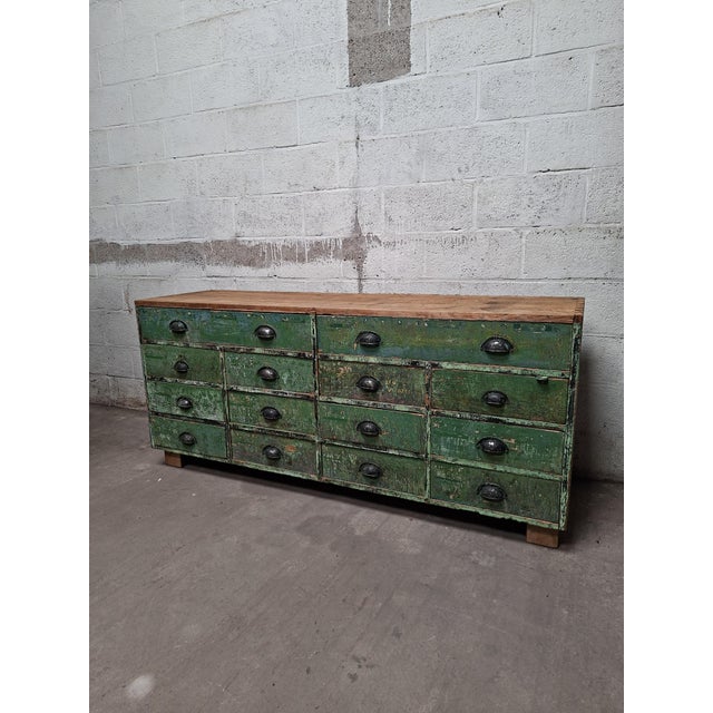 Robust vintage wooden drawer cabinet from a former workshop, finished with a deep green patina. Its long, low proportions...