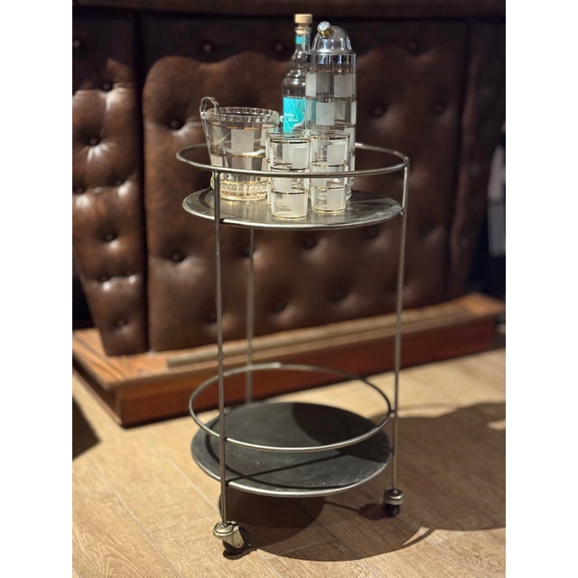 This vintage two-tier metal bar cart features a clean, circular silhouette with minimalist architectural lines....