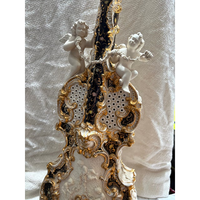 Capodimonte porcelain table lamp features a violin shape decorated with cherub figurines and gold accents, also comes with...
