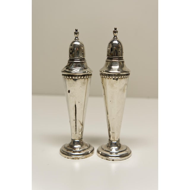 A pair of monogramed "M" weighted sterling silver salt and pepper shakers with screw-on lids, likely dating from the late...
