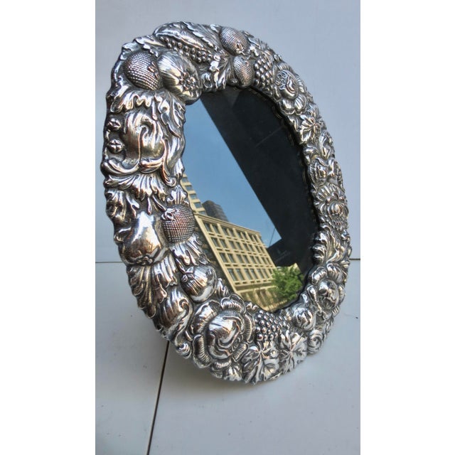 Large oval format frame with a border of textured flowers and fruits. Elaborate design in relief. No maker's marks are...
