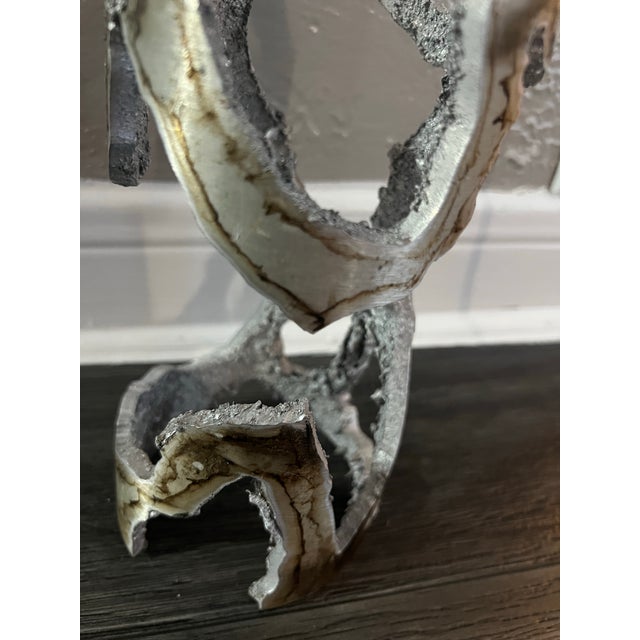 Modern pendant/lamp with a silver and white finish, visible bulb socket, and cord. Handmade cast metal design with a...