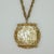 Ornate Miriam Haskell gold plated medallion pendant suspended from a twisted chain link necklace outfitted with a safety...