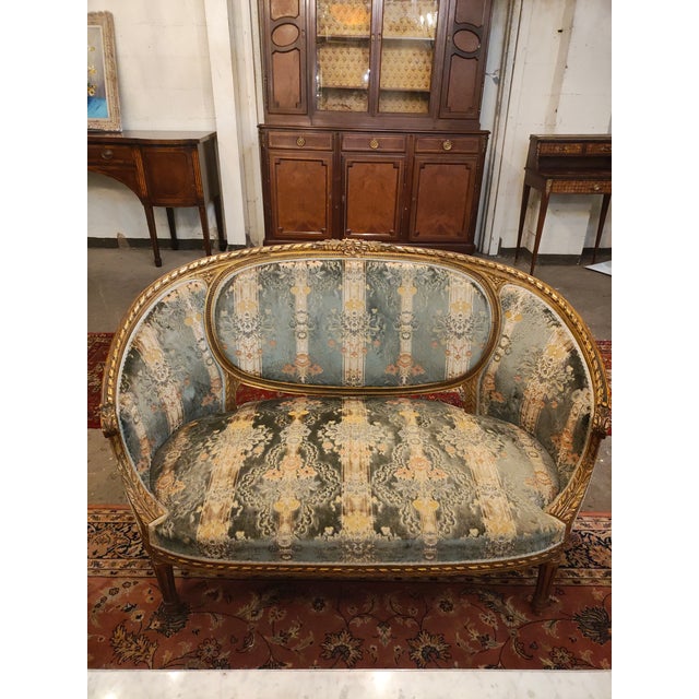 Antique French giltwood salon seating set dating to circa 1900, consisting of one settee and four matching armchairs. The...