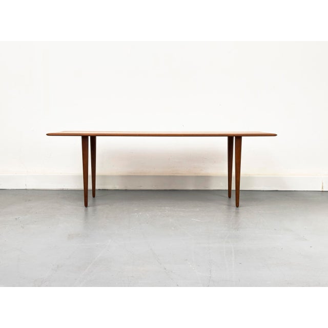 A delicate Danish coffee table by France & Søn. It is made of solid teak with tapered edges and slender, tapered legs....